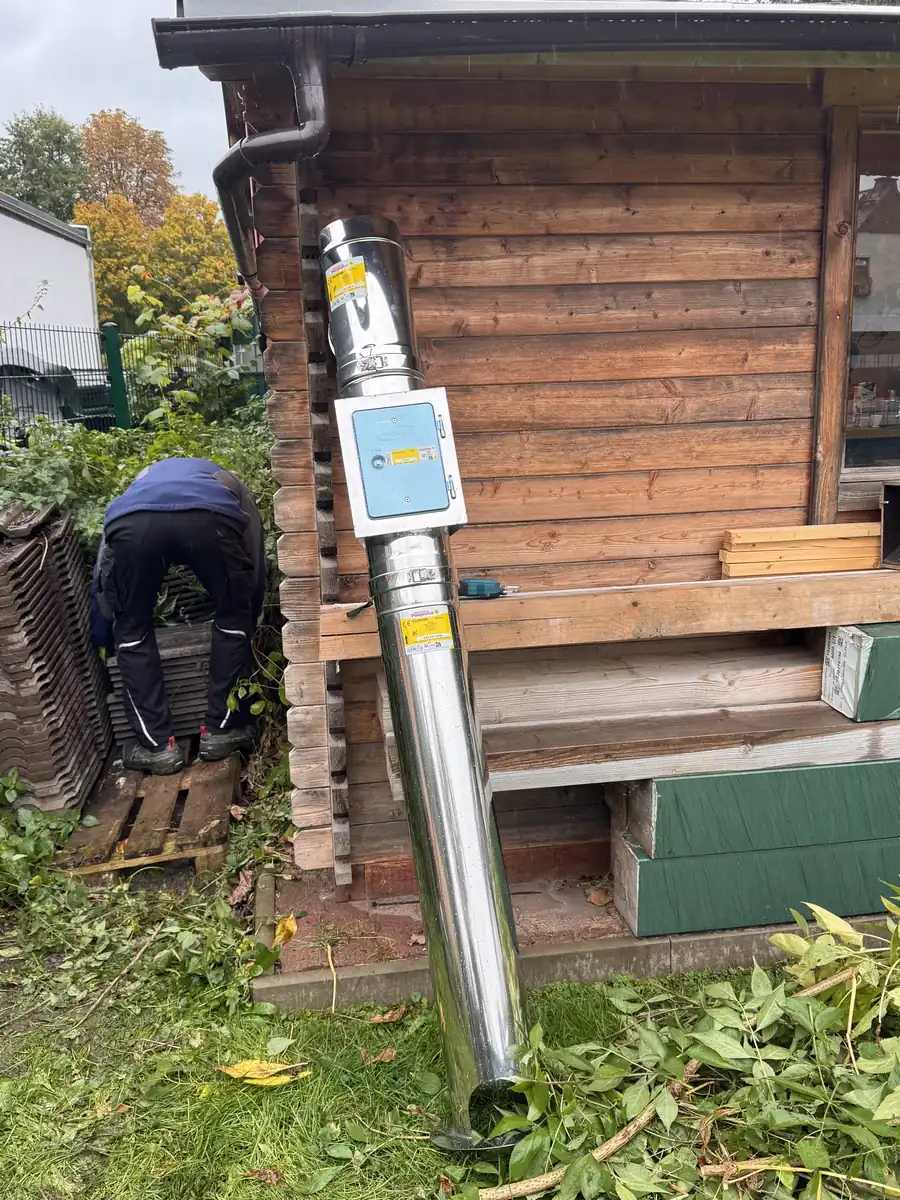 Das Schornsteinrohr wird an der Au&szlig;enwand der Gartenlaube aufgebaut